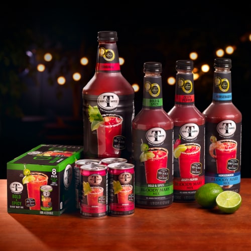 Mr. & Mrs. T Bloody Mary mix bottles and cans with fresh lime on a bar table